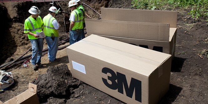 Dozen met 3M-producten op de grond in de buurt van werknemers
