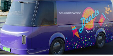 Paarse bestelwagen gewrapt in kleurrijke 3M-graphics met het merk van een donutbakkerij.
