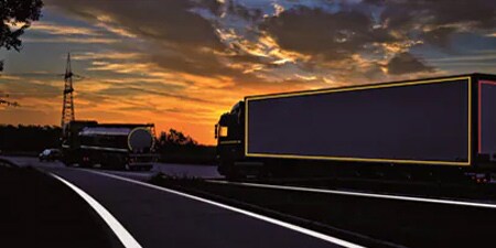 Vrachtwagen op een donkere weg met zichtbare contourmarkeringen
