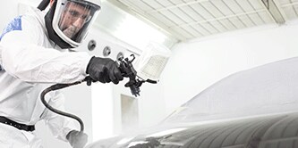 Lakspecialist die een voertuig spuit
