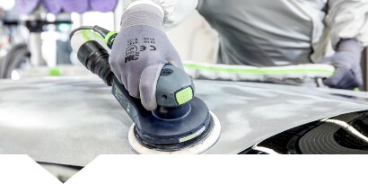 Technicus die een beschadigd autopaneel schuurt
